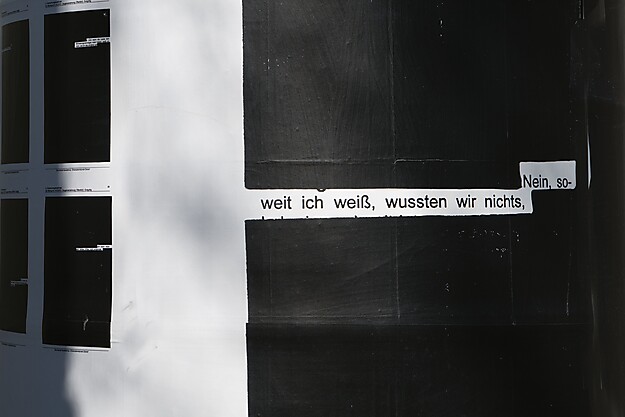 Detailaufnahme einer Litfaßsäule mit Plakat eines geschwärzten Blattes, auf dem lediglich "Nein, soweit ich weiß, wussten wir nichts" zu lesen ist.